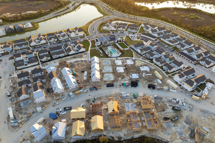 Unfinished frames of inexpensive homes with wooden roof beams under construction. Development of residential housing in US suburbs. Real estate market in the USA.